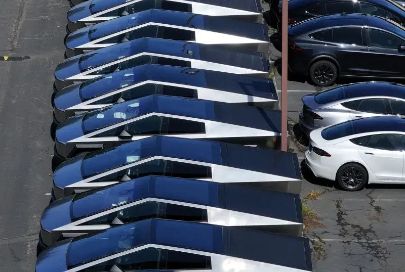 صف من سيارات تسلا الكهربائية، بما في ذلك طراز Cybertruck، متوقفة في موقف سيارات، مما يعكس تراجع مبيعات الشركة وسط الاحتجاجات ضد إيلون ماسك.