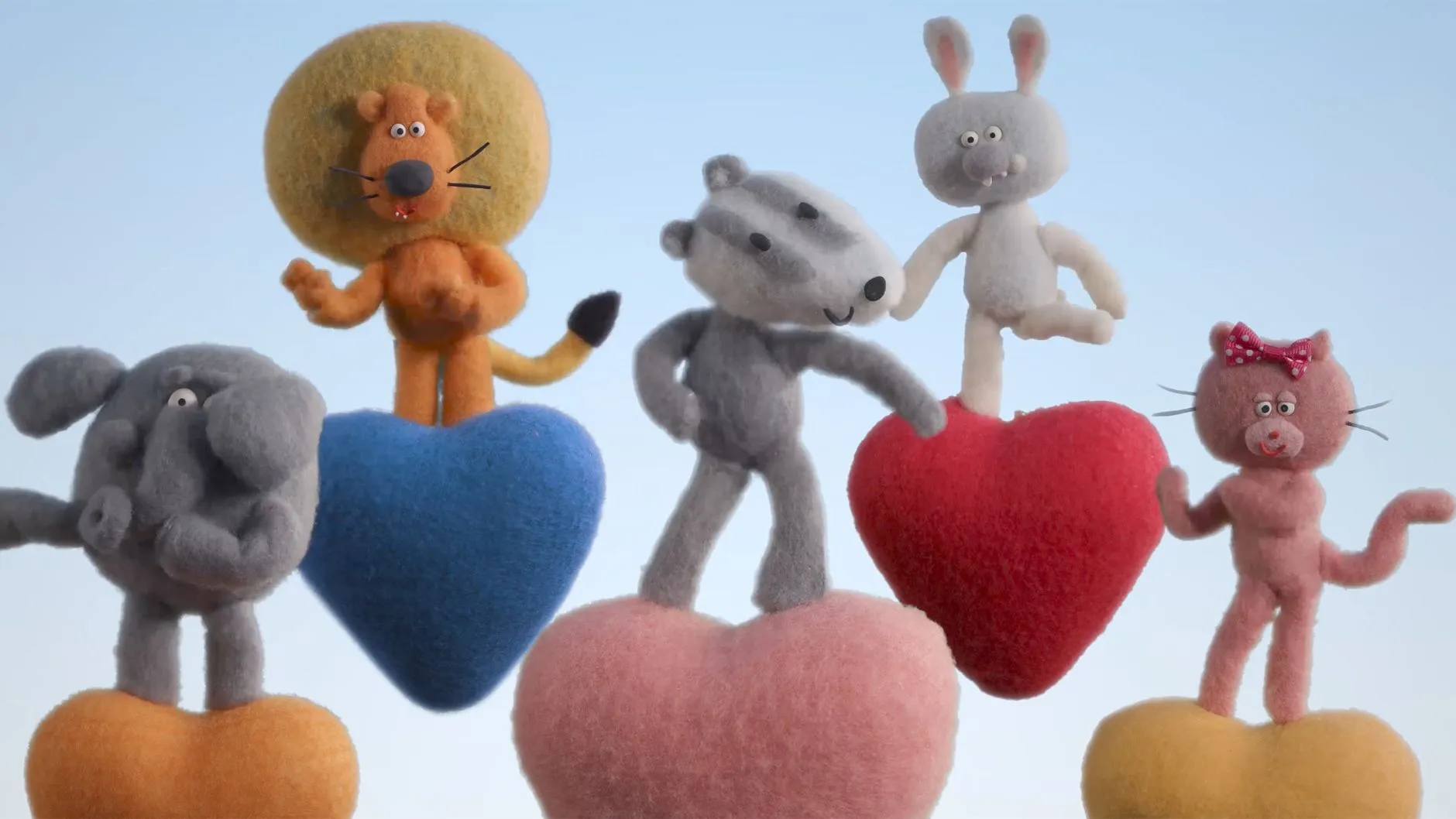 دمى محشوة على شكل حيوانات لطيفة تقف على قلوب ملونة، تعبر عن أجواء السعادة والراحة التي توفرها أغنية "The Happy Song" لتهدئة الرضع.