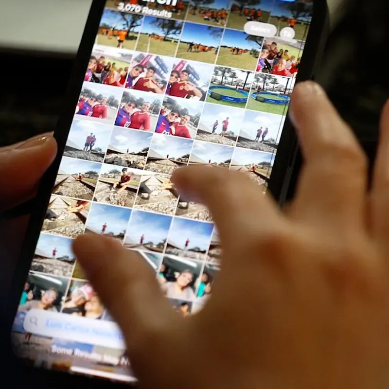 شخص يستخدم هاتفه المحمول لتصفح مجموعة من الصور، مما يعكس التواصل والذكريات المرتبطة بالجالية الفنزويلية في الولايات المتحدة.