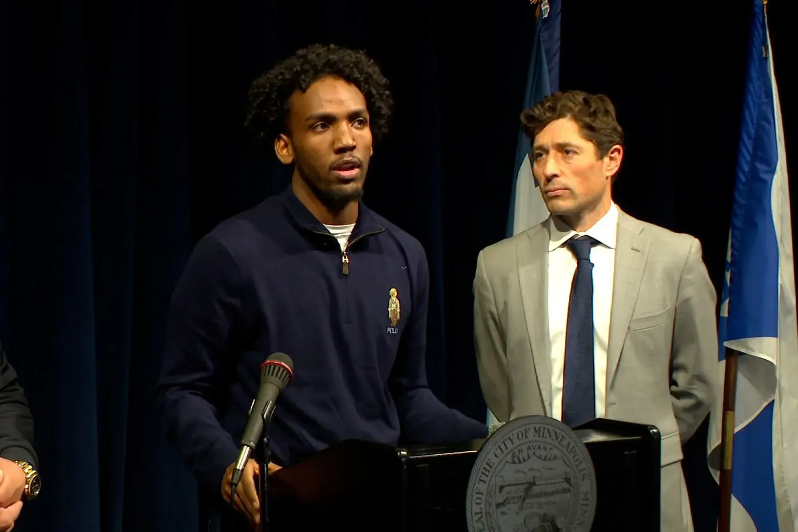 مبشر يتحدث في مؤتمر صحفي، مع وجود مسؤول بجانبه، حول تجربة احتجازه من قبل عملاء فيدراليين في مينيابوليس.