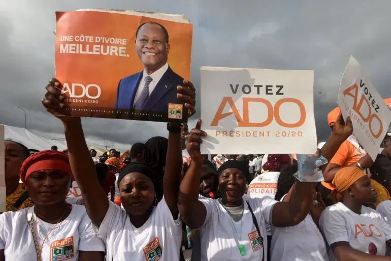 مؤيدو المرشح الرئاسي تيجان تيام يتظاهرون في أبيدجان، حاملين لافتات تحمل شعارات دعم، وسط أجواء من الأمطار والقلق السياسي.