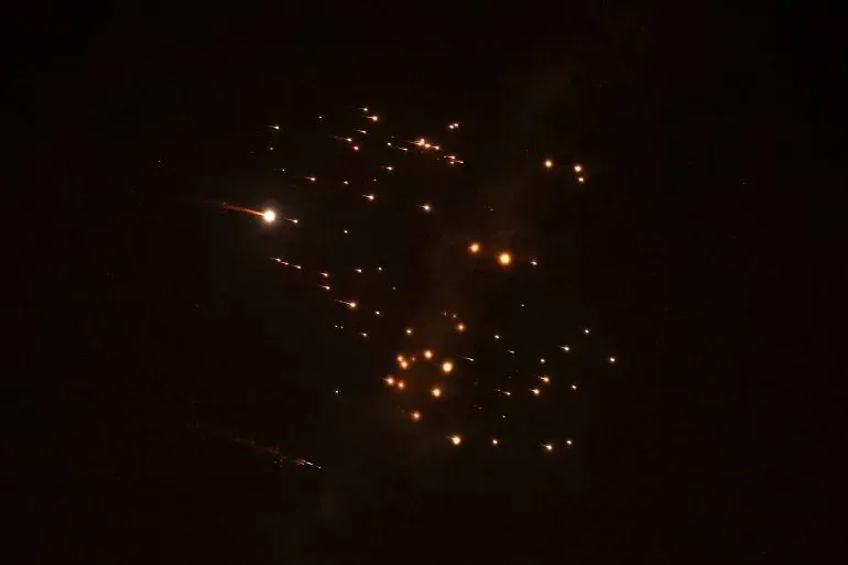 شظايا صاروخية تتساقط في السماء ليلاً، مما يعكس الأثر المدمر للهجمات الإيرانية على المناطق الفلسطينية، حيث قُتلت ثلاث نساء في صالون.