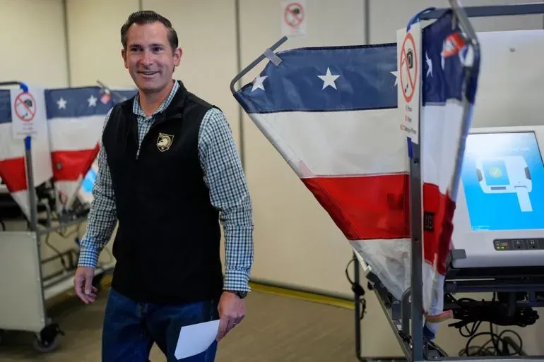 ناخب مبتسم يقف بجانب آلة الاقتراع في مركز انتخابي بولاية تينيسي، حيث تجري انتخابات مهمة للدائرة السابعة للكونغرس.