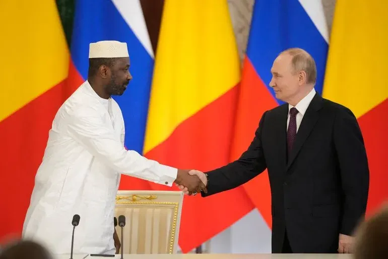 اجتماع بين رئيس مالي باه نداو والرئيس الروسي فلاديمير بوتين، حيث يتصافحان وسط أعلام الدول، في إطار تعزيز التعاون الأمني.