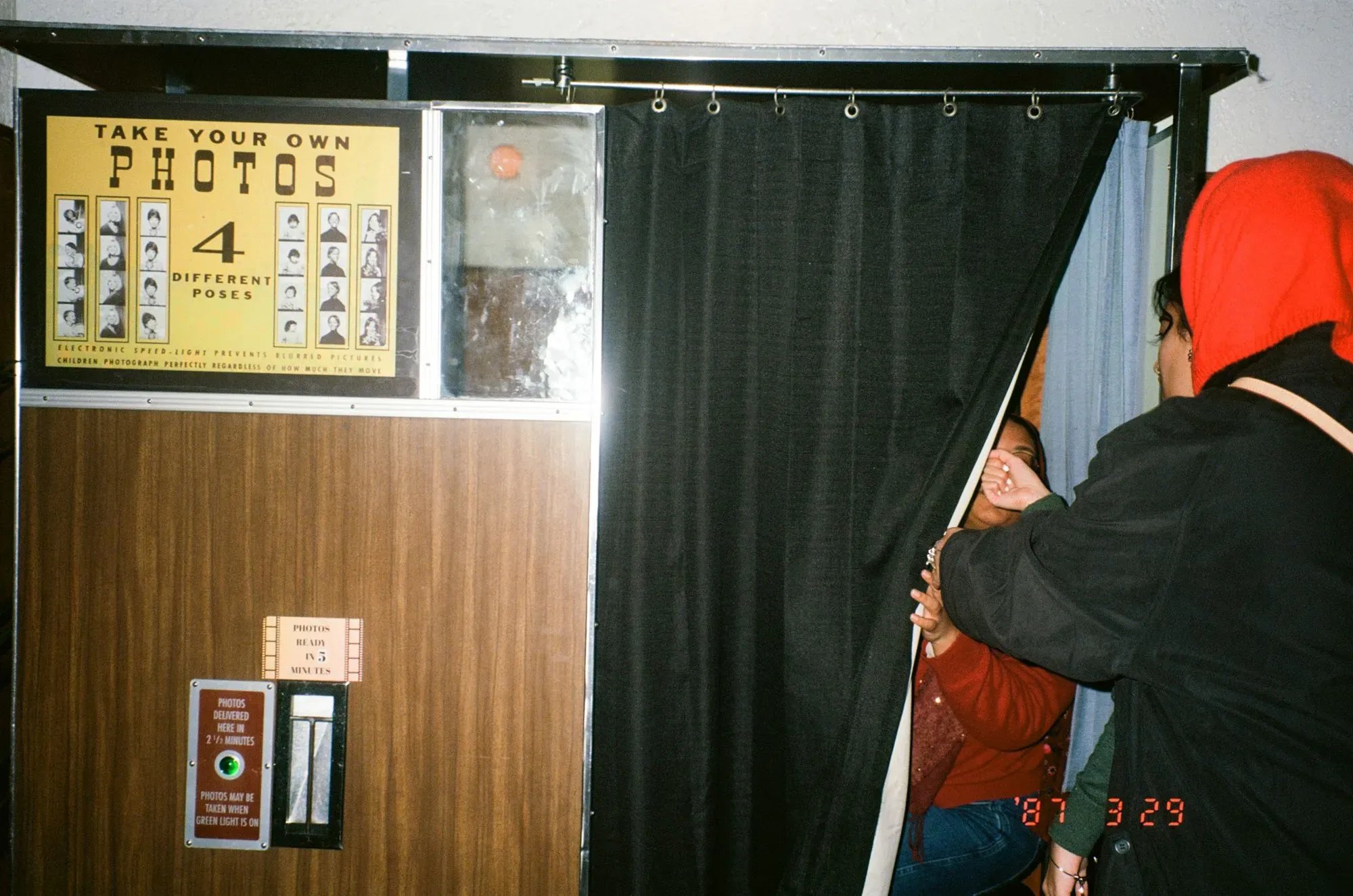 آلة تصوير قديمة مع لافتة توضح كيفية التقاط صور بأربع أوضاع مختلفة، بينما تتجمع مجموعة من الأشخاص حولها.