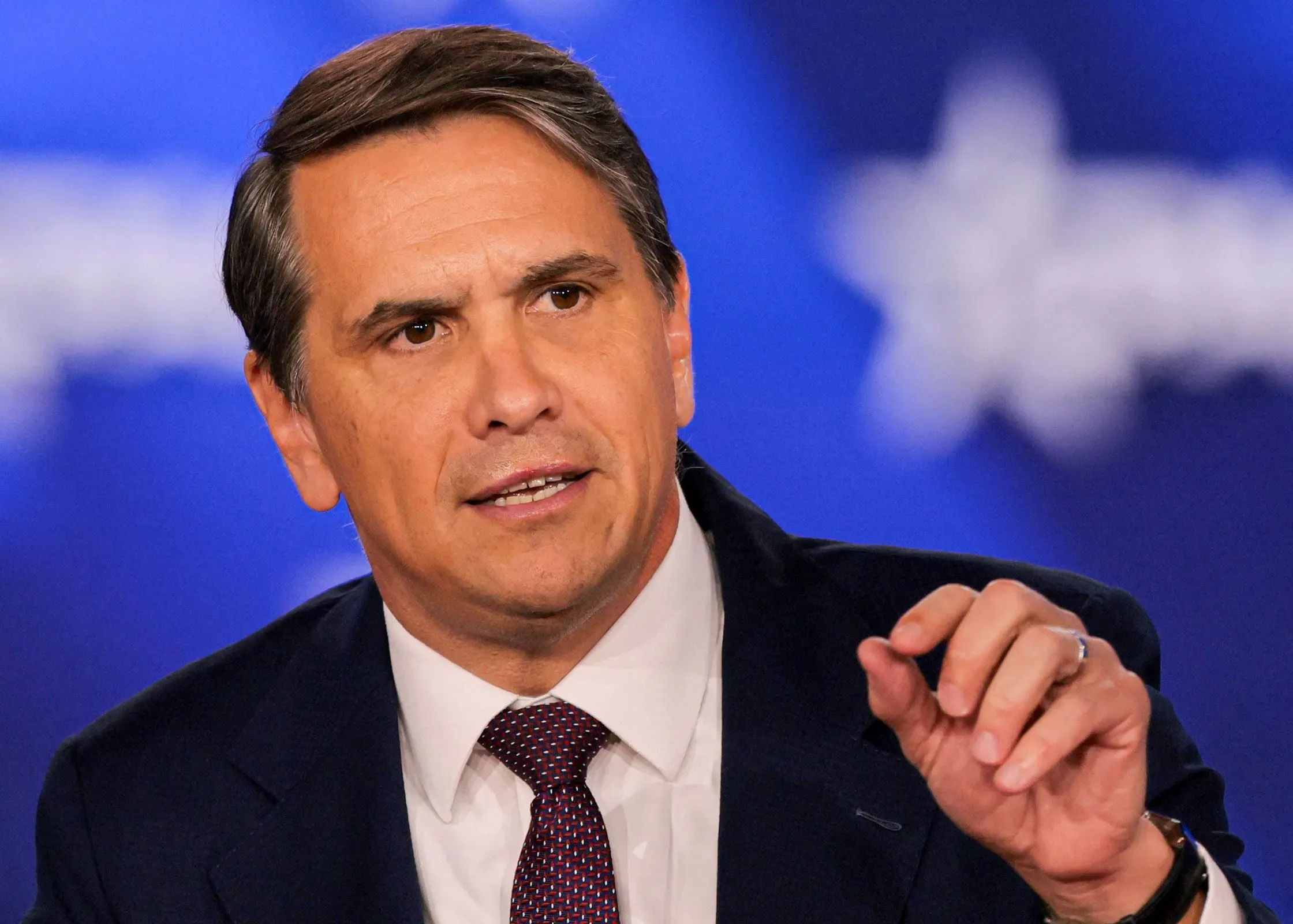 تود بلانش يتحدث في مؤتمر، مع التركيز على قضايا وزارة العدل وعلاقته بالرئيس ترامب، وسط خلفية زرقاء.