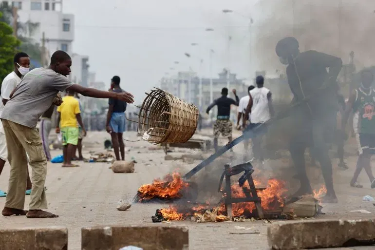 محتجون في لومي، توغو، يتظاهرون ضد الحكومة، بينما تشتعل النيران في الشارع، مما يعكس حالة التوتر السياسي في البلاد.