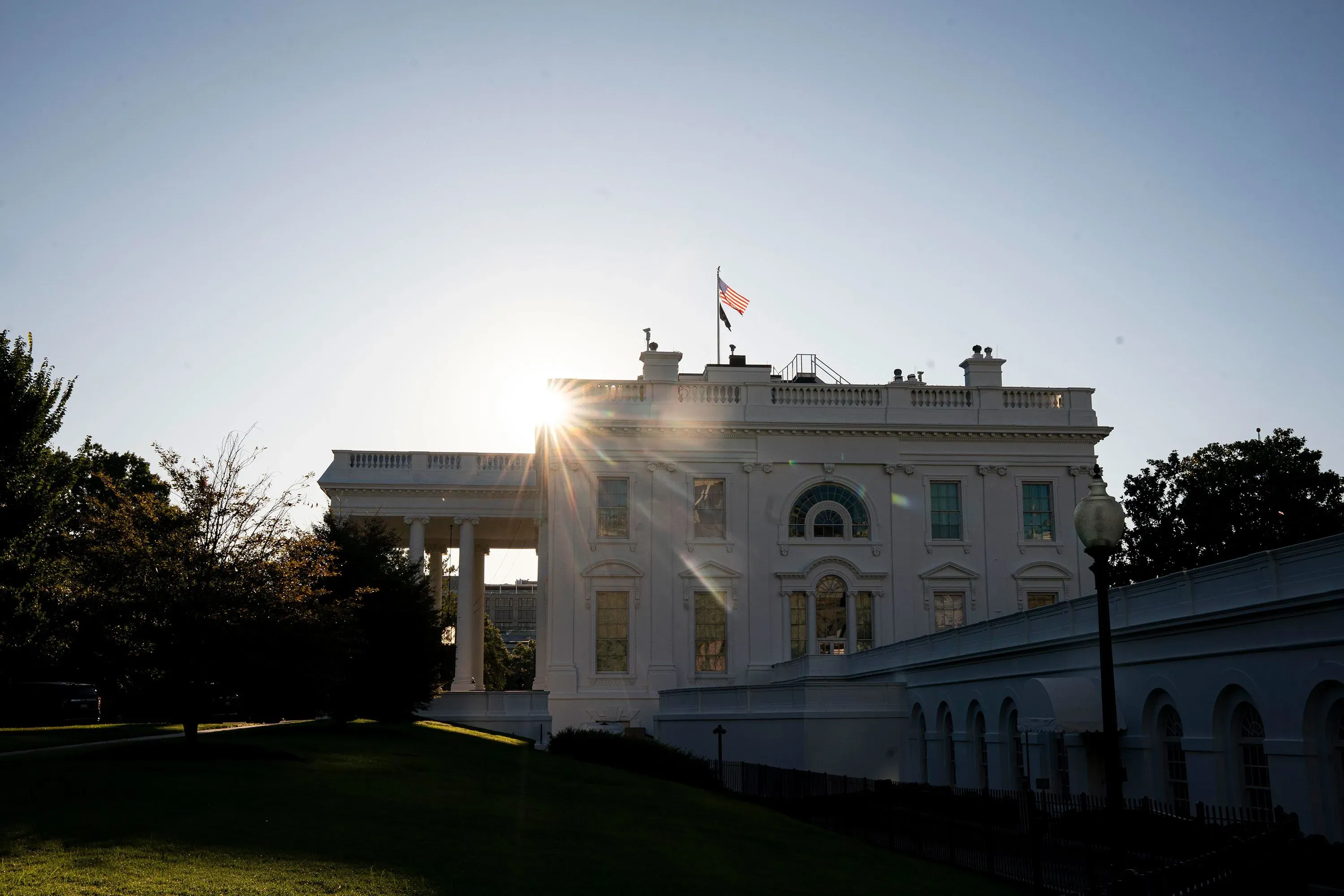 البيت الأبيض يتعرض لأشعة الشمس مع العلم الأمريكي يرفرف، في وقت يجتمع فيه قادة الكونجرس مع الرئيس ترامب لتجنب الإغلاق الحكومي.