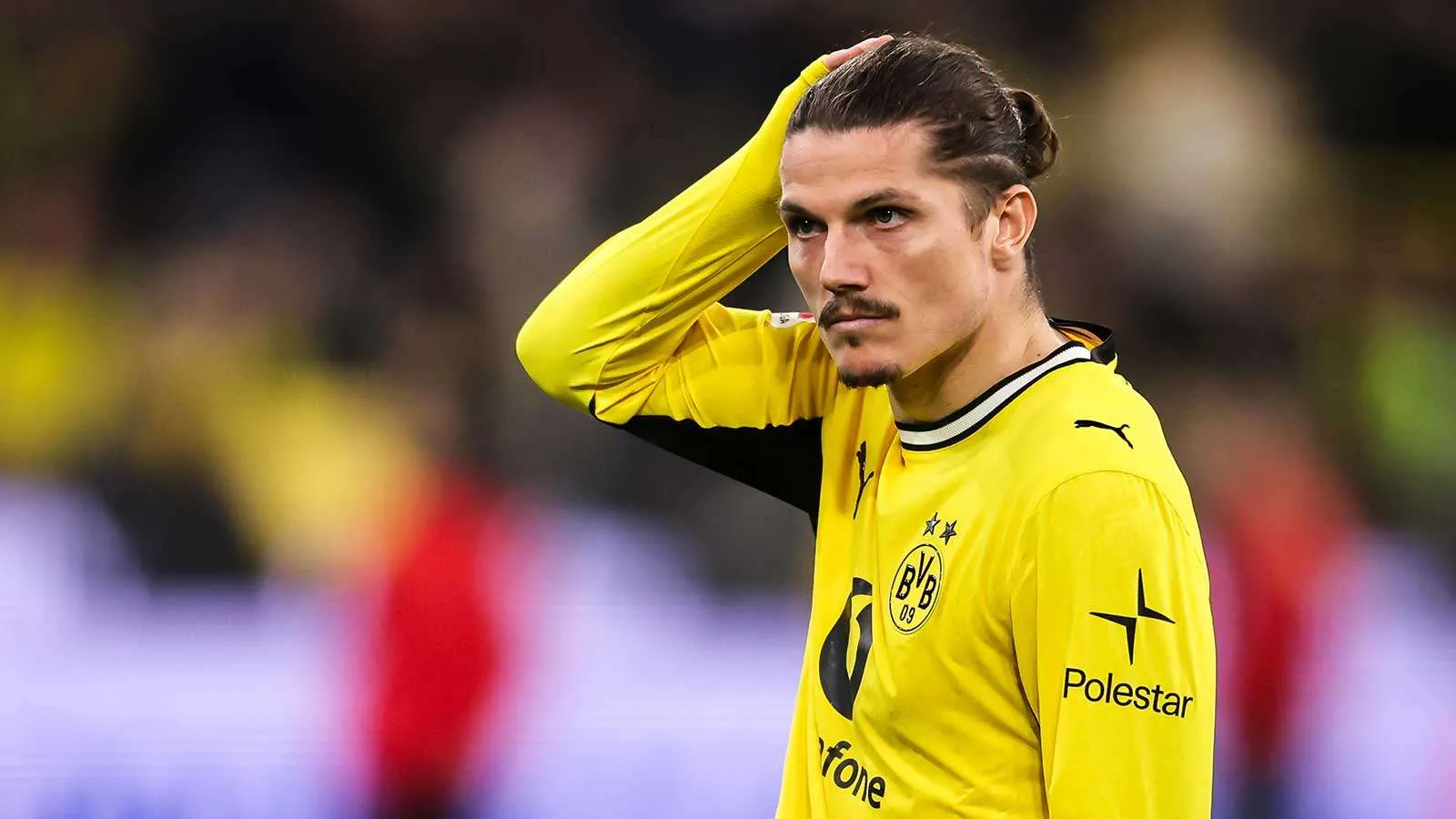 لاعب وسط بوروسيا دورتموند مارسيل سابيتزر يرتدي قميص الفريق الأصفر خلال مباراة، مع تسليط الضوء على احتمالية انتقاله إلى بولونيا رغم التحديات المالية والرياضية.
