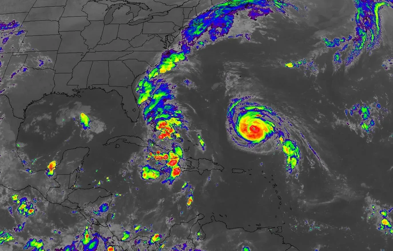 تظهر الصورة خريطة للأقمار الصناعية توضح موقع العاصفة الاستوائية إيميلدا وإعصار هامبرتو في المحيط الأطلسي، مع تباين الألوان للدلالة على قوة العواصف.