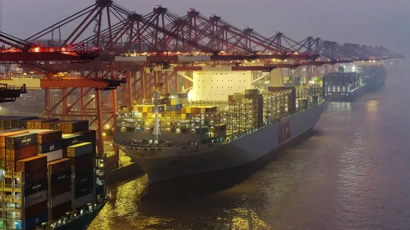 سفينة شحن كبيرة محملة بالحاويات ترسو في ميناء صيني، مما يعكس النشاط التجاري المتزايد في العلاقات الاقتصادية بين الولايات المتحدة والصين.