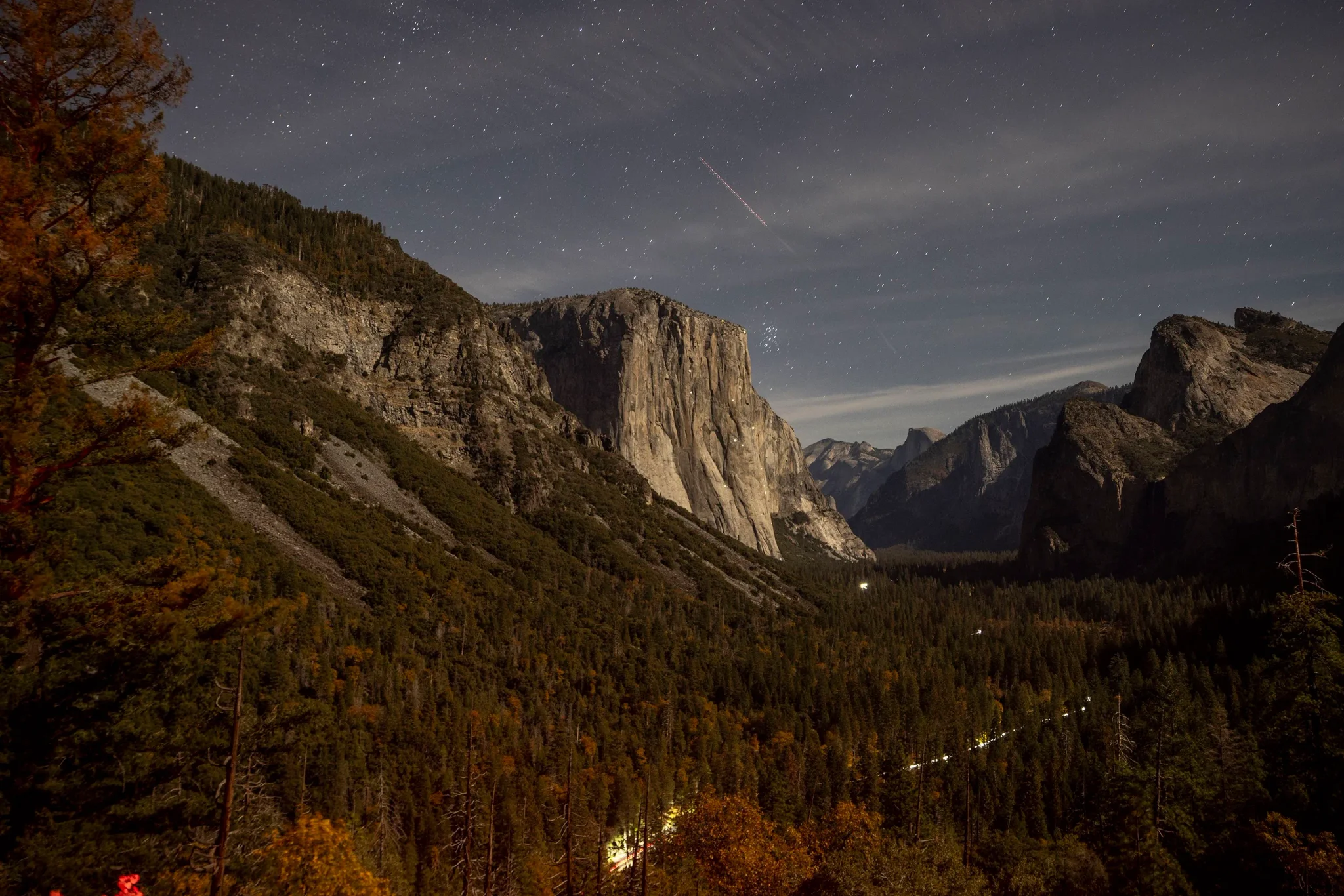منظر ليلي لوادي Yosemite الوطني في كاليفورنيا يظهر الجبال والغابات تحت سماء مرصعة بالنجوم، مع تهديد مشروع طريق عقاري لحرمة المتنزه.