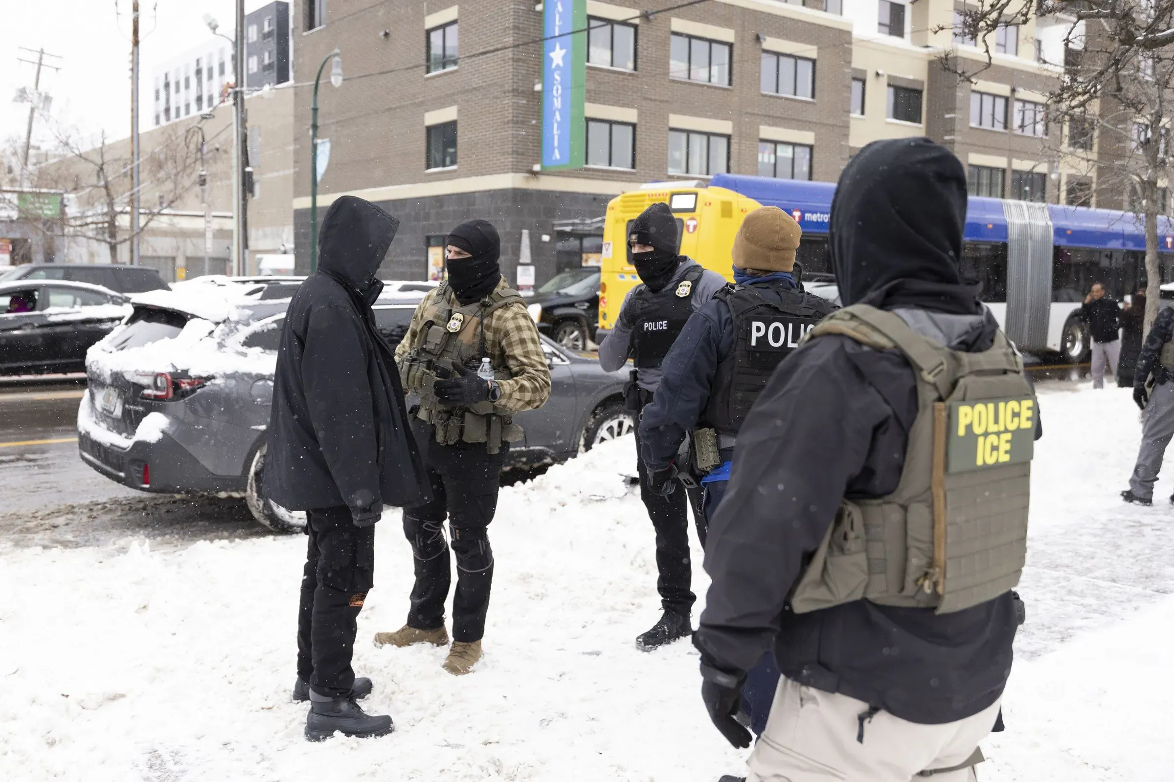 انتشار عملاء إدارة إنفاذ قوانين الهجرة والجمارك في مينيابوليس، حيث يتحدثون مع أفراد في منطقة مغلقة بالثلوج، وسط توتر متزايد حول قضايا الهجرة.