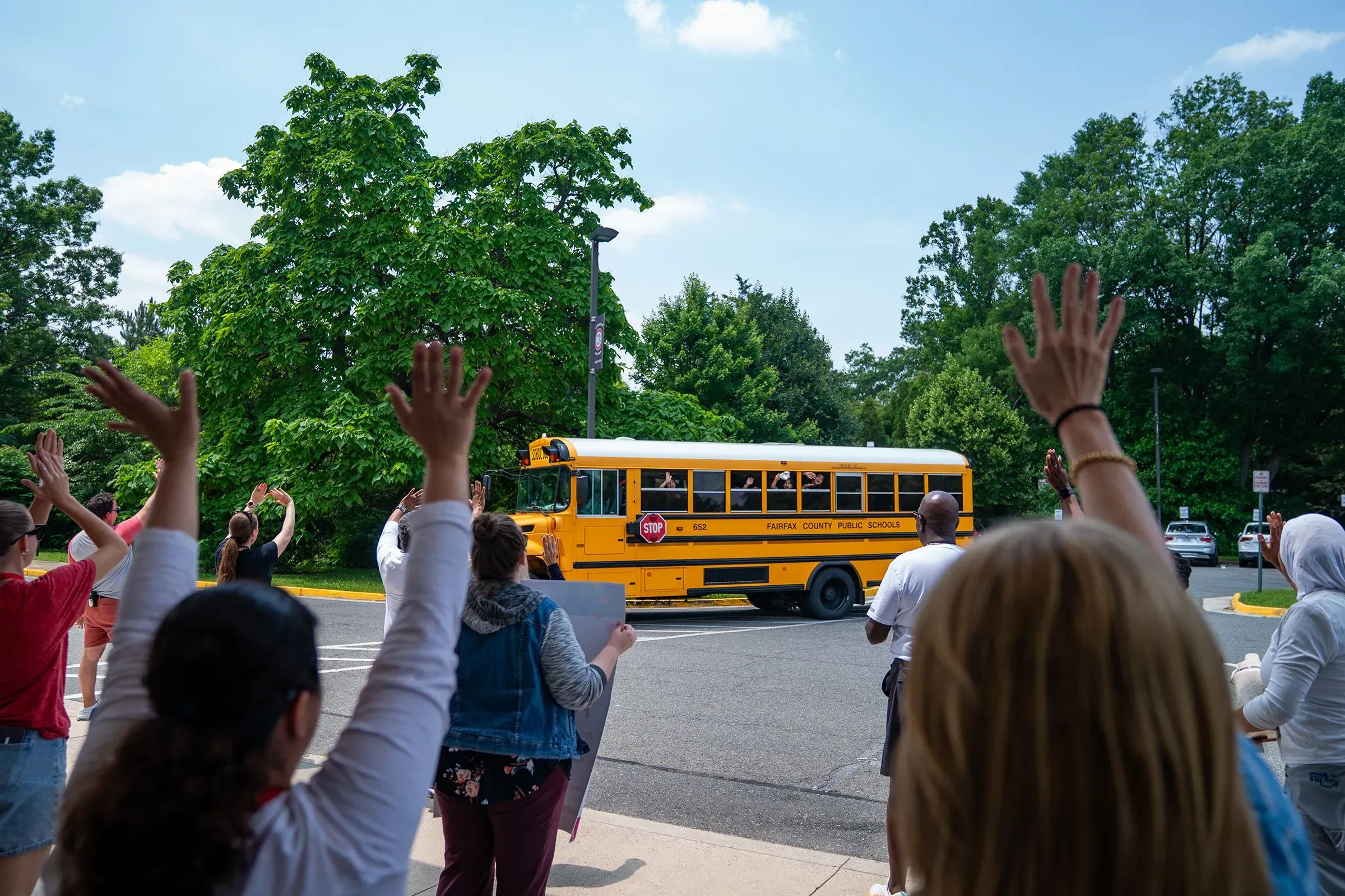 طلاب يلوحون بأيديهم لباخرة مدرسية صفراء أثناء مغادرتها، مما يعكس الحماس والارتباط بالمؤسسات التعليمية.