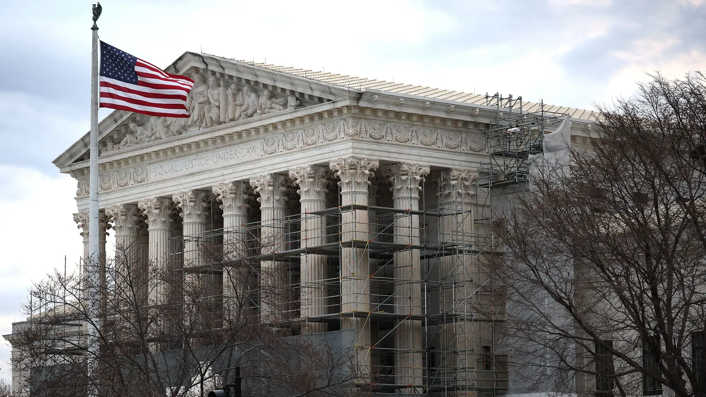 مبنى المحكمة العليا الأمريكية مع أعمدة بارزة، علم الولايات المتحدة يرفرف في المقدمة، وأعمال ترميم جارية على الهيكل.