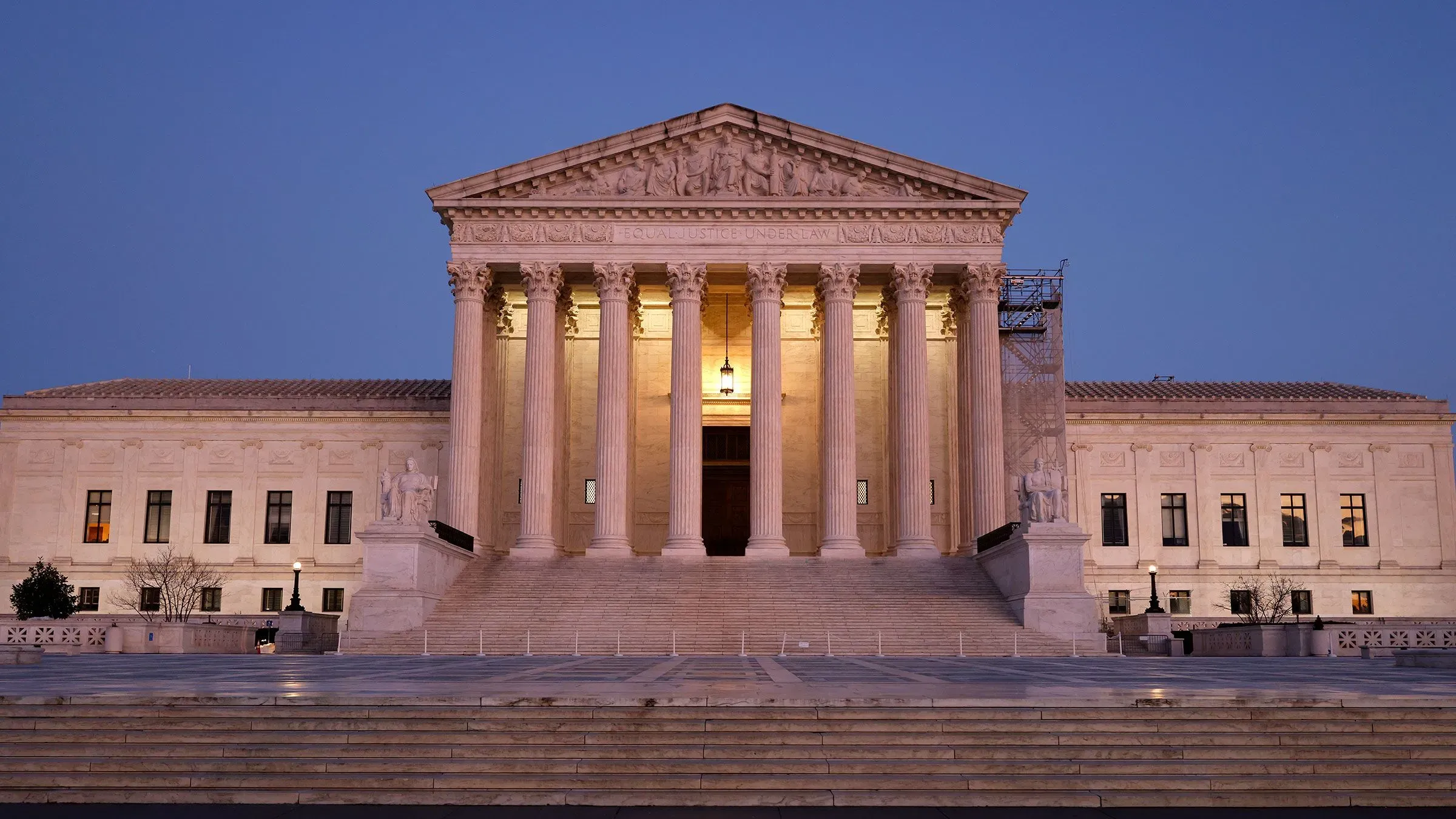 واجهة المحكمة العليا الأمريكية مضاءة في المساء، مع أعمدة ضخمة تعكس أهمية القضايا القانونية المتعلقة بإدارة ترامب.