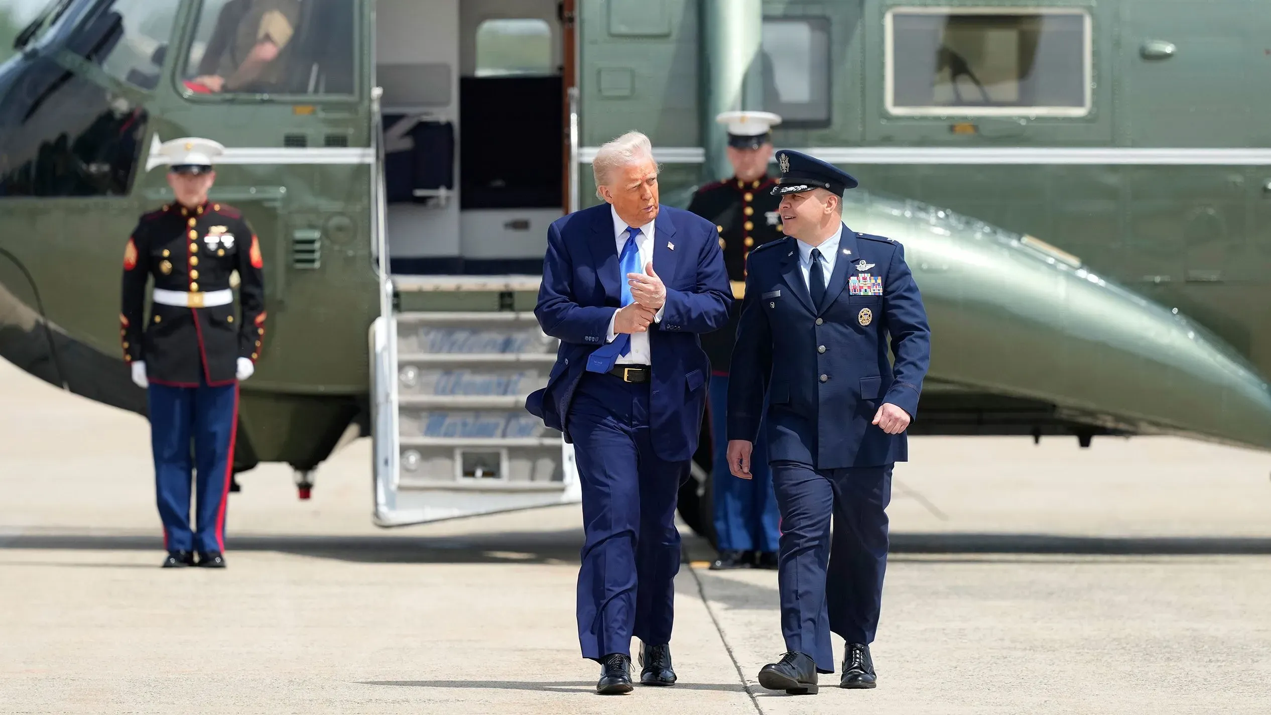 ترامب يتحدث مع ضباط عسكريين أثناء مغادرته مروحية في قاعدة عسكرية، في سياق محادثات السلام المحتملة بين روسيا وأوكرانيا.