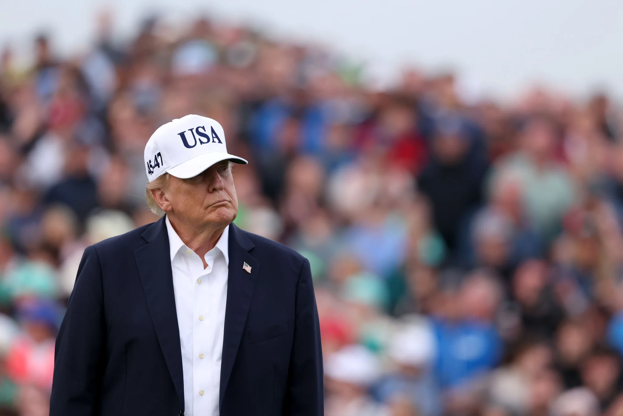 الرئيس الأمريكي دونالد ترامب يرتدي قبعة بيضاء مكتوب عليها USA، وسط جمهور كبير، معبرًا عن موقفه الحاد من تنظيم الذكاء الاصطناعي.