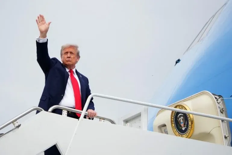 ترامب يلوح بيده أثناء صعوده إلى الطائرة الرئاسية، مما يعكس نشاطاته المالية وتأثيرها على ثروته الشخصية.