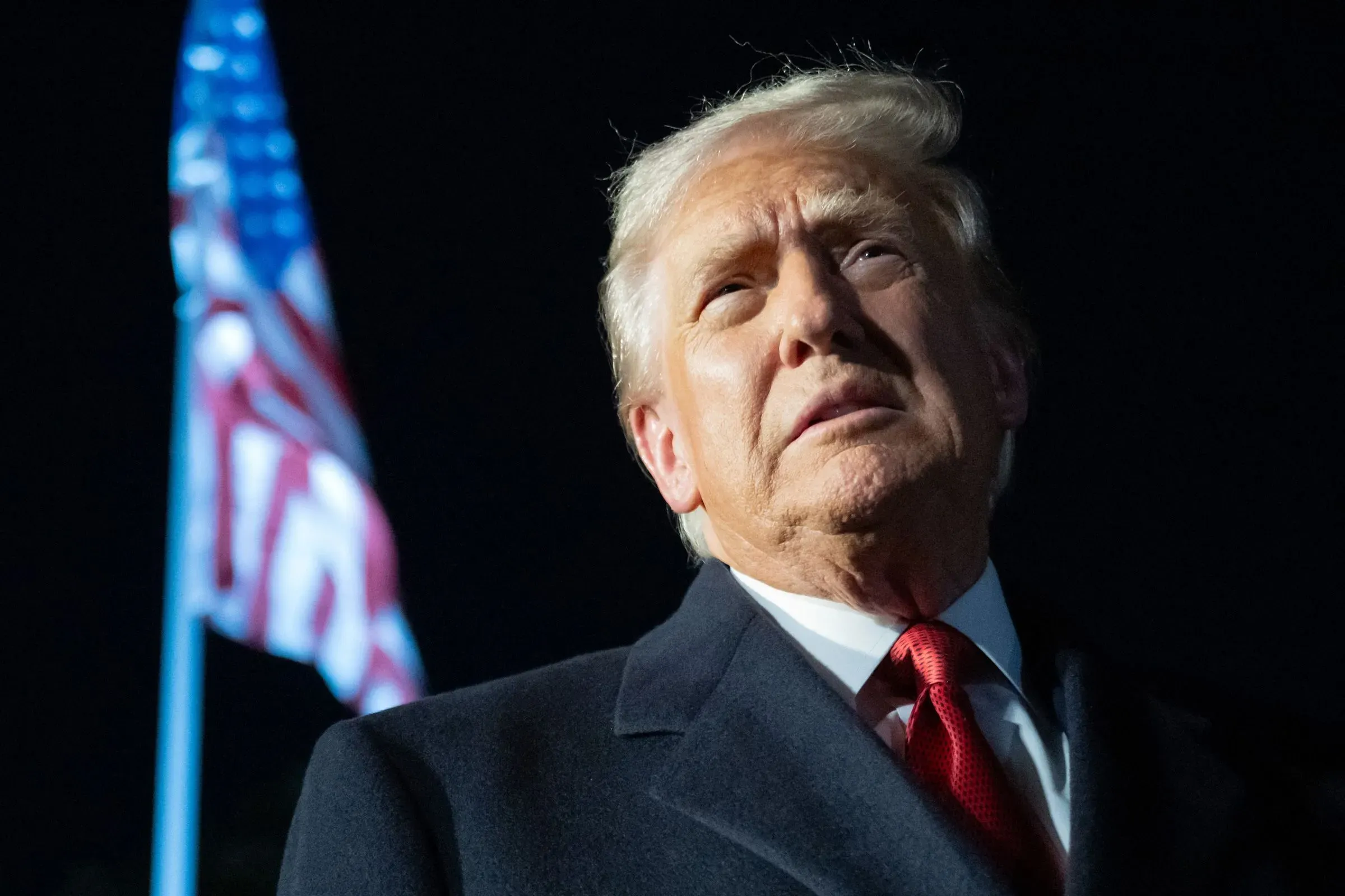 تصريح ترامب حول اختبار الأسلحة النووية الأمريكية يتزامن مع توترات جيوسياسية متزايدة، مع العلم أن العلم الأمريكي يرفرف خلفه.