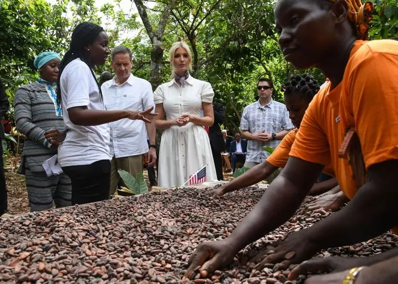 إيفانكا ترامب تتفاعل مع نساء محليات خلال حدث زراعي، حيث يشاركن في عملية تجهيز حبوب الكاكاو، مما يعكس جهود تمكين المرأة.
