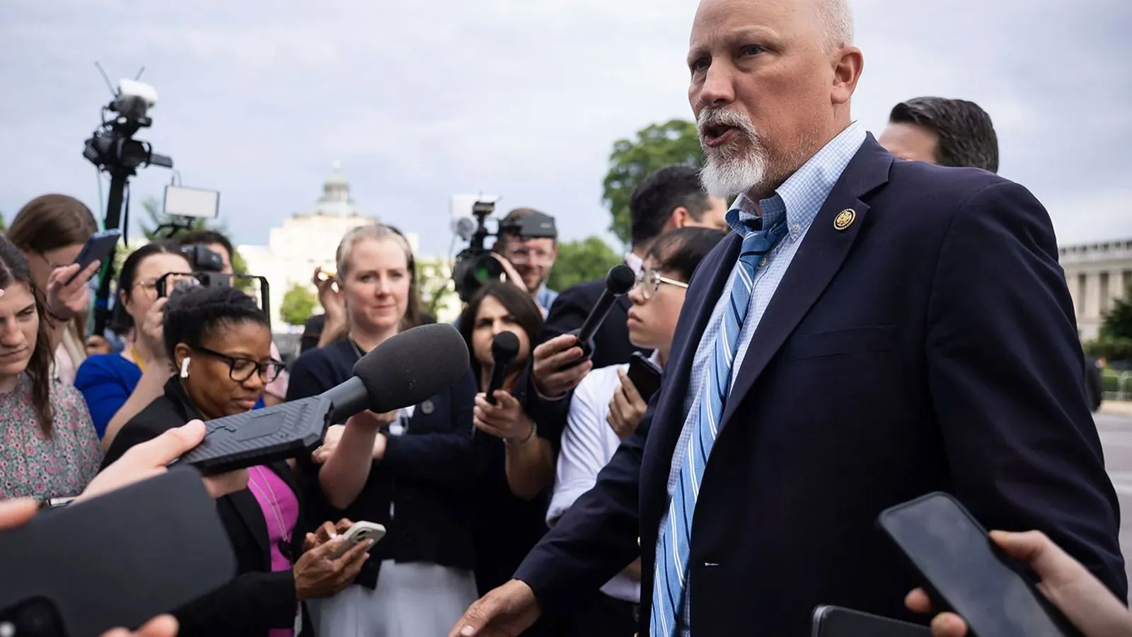 تشيب روي يتحدث للصحفيين وسط مجموعة من المراسلين، مع التركيز على قضايا تشريعية مهمة تتعلق بمشروع قانون ترامب.