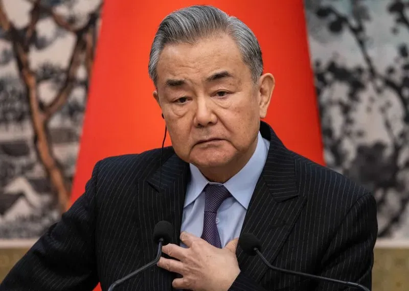 وزير الخارجية الصيني وانغ يي يتحدث في مؤتمر صحفي، مع خلفية حمراء، معبرًا عن موقف الصين في ظل تصاعد التوترات التجارية مع الولايات المتحدة.