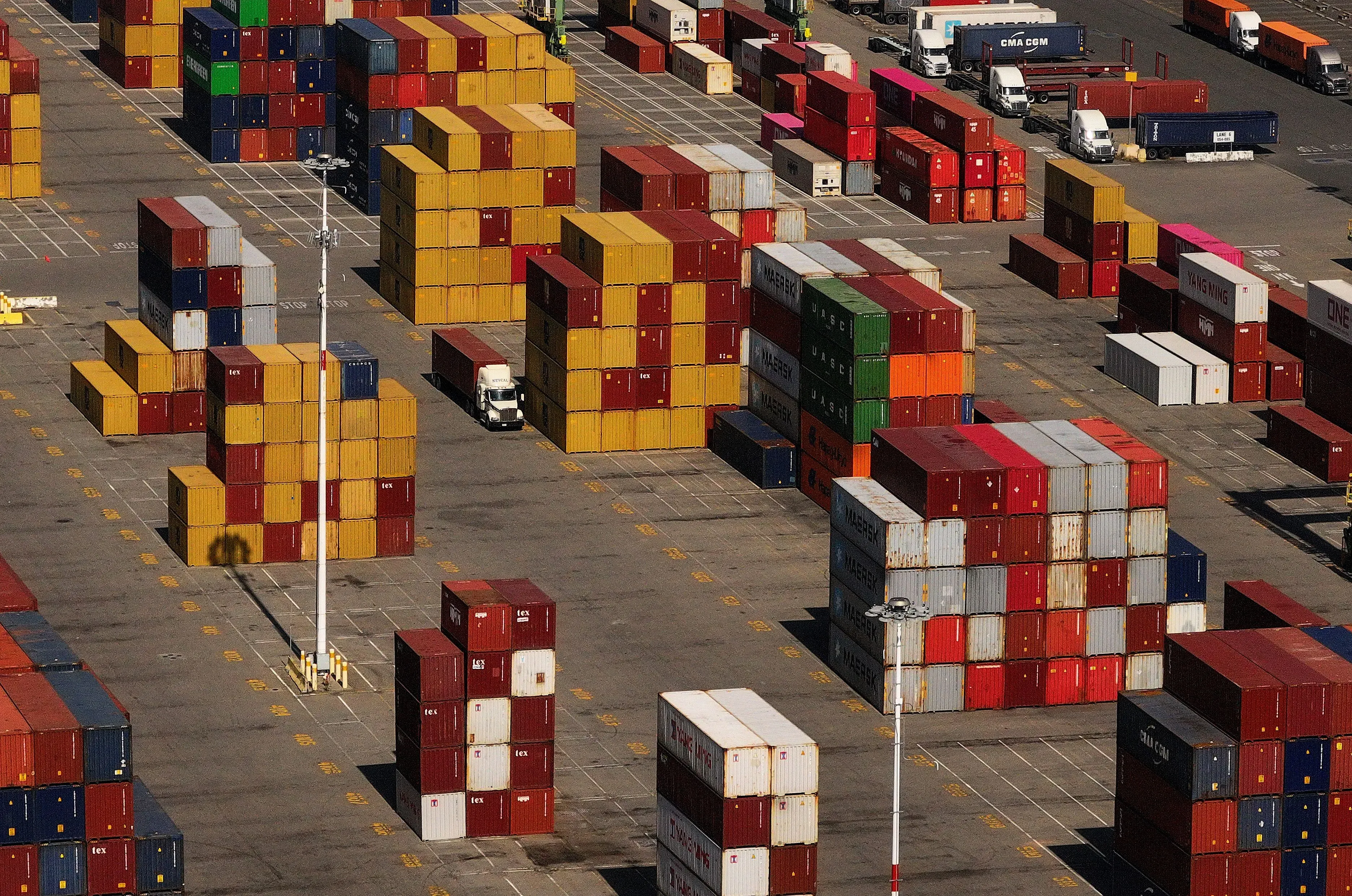 صورة لمستودع يحتوي على حاويات شحن ملونة مرتبة بشكل منظم، تعكس التغيرات في التعريفات الجمركية الأمريكية وتأثيرها على التجارة الدولية.