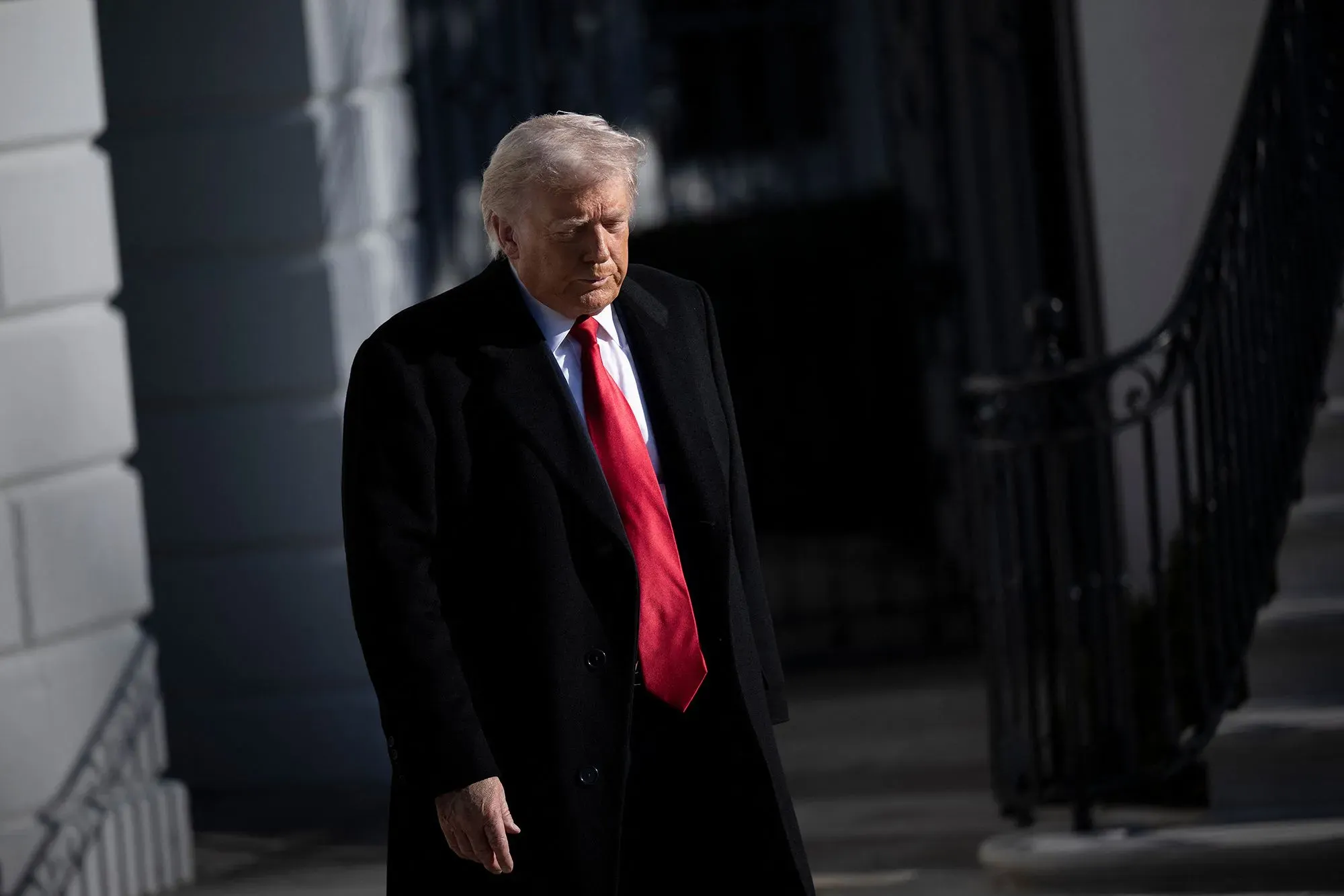 ترامب يسير بخطوات واثقة خارج البيت الأبيض، مرتديًا سترة داكنة وربطة عنق حمراء، في سياق مناقشات حول الأمن في فنزويلا.