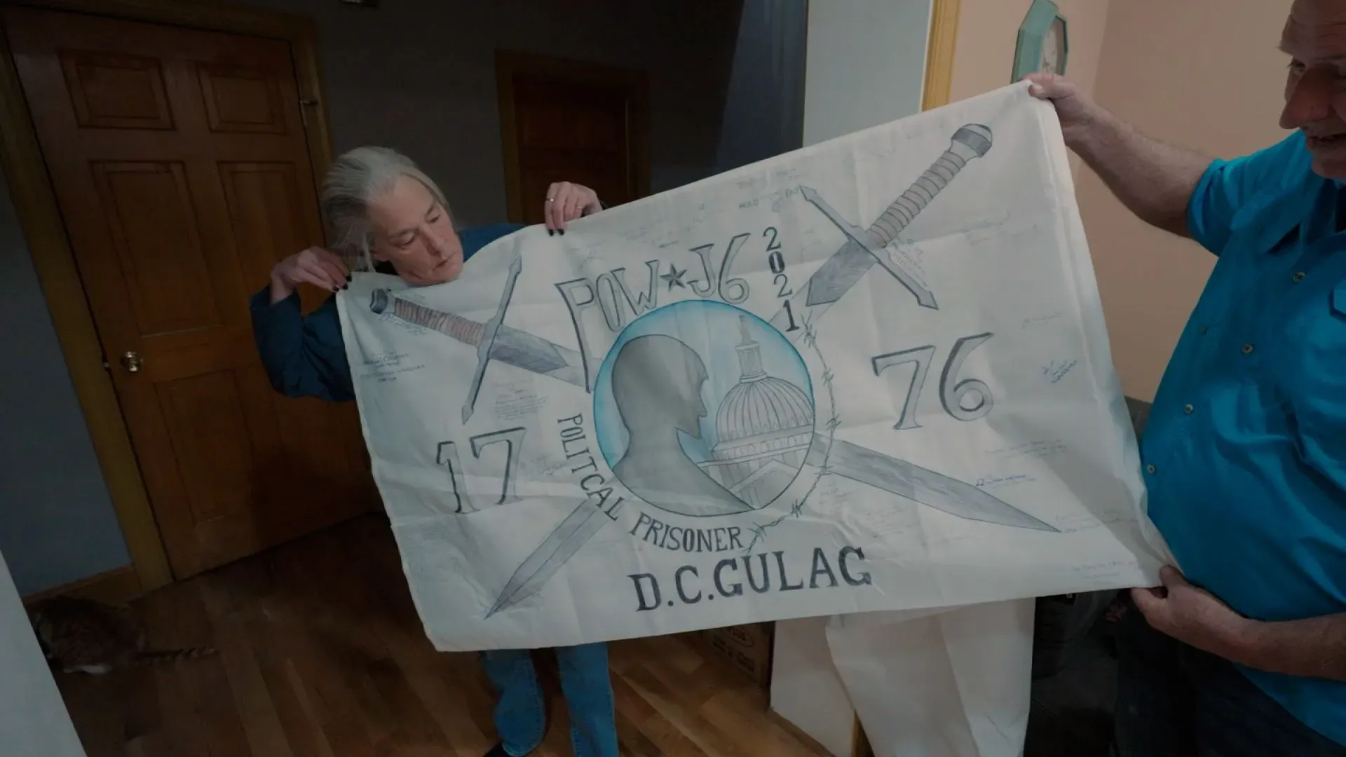 رجل يحمل لافتة تعبر عن تضامنه مع المسجونين السياسيين بعد أحداث 6 يناير، تظهر تصميمًا يتضمن رموزًا تاريخية وكلمات دالة على الظلم.