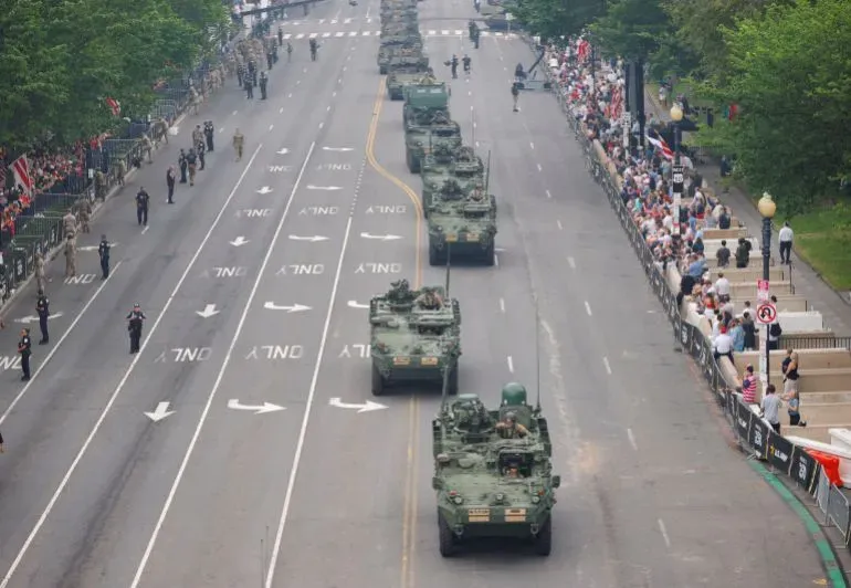 عرض عسكري في واشنطن العاصمة بمناسبة عيد ميلاد الجيش الأمريكي، مع تقدم دبابات ومركبات عسكرية في الشارع وسط حشد من المتفرجين.