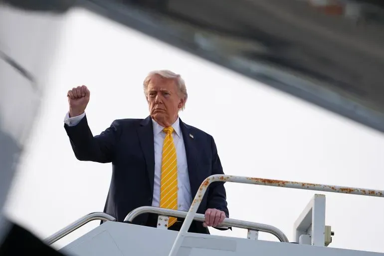 الرئيس الأمريكي دونالد ترامب يرفع يده في إشارة أثناء صعوده على متن طائرة Air Force One، مع خلفية توتر العلاقات مع إيران.