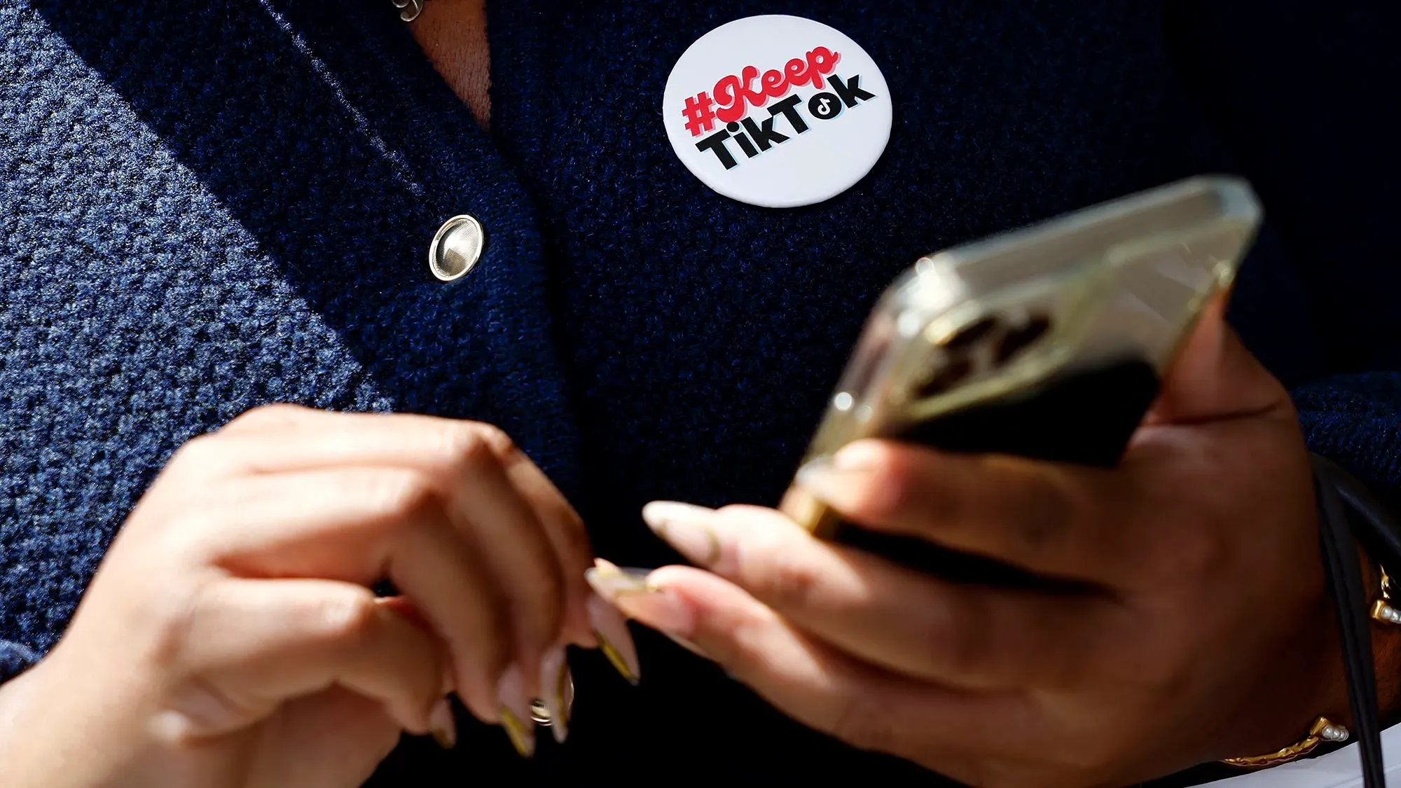 شخص يحمل هاتفًا ذكيًا ويضغط على زر يحمل عبارة ""، رمزية للاحتجاج على مخاوف الأمن القومي المرتبطة بتطبيق تيك توك.