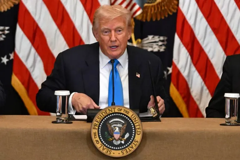 دونالد ترامب يتحدث خلال مؤتمر صحفي في البيت الأبيض، مع أعلام أمريكية خلفه، في إطار حملة للترويج للسياسات الاقتصادية.