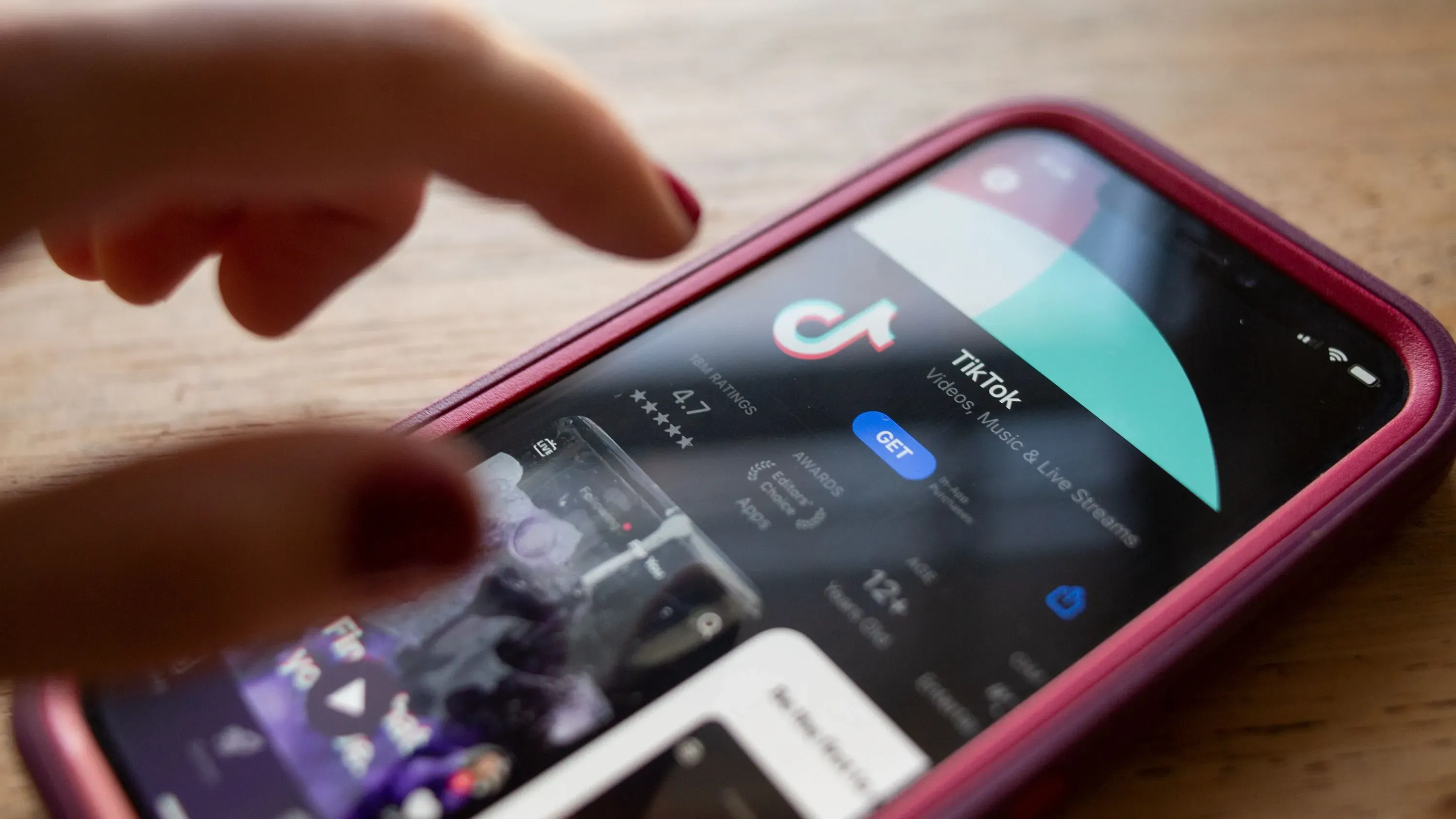 تظهر الصورة شاشة هاتف محمول تعرض تطبيق TikTok، مع التركيز على زر التنزيل وتقييم التطبيق، مما يعكس الاهتمام المتزايد بالمنصة في الولايات المتحدة.