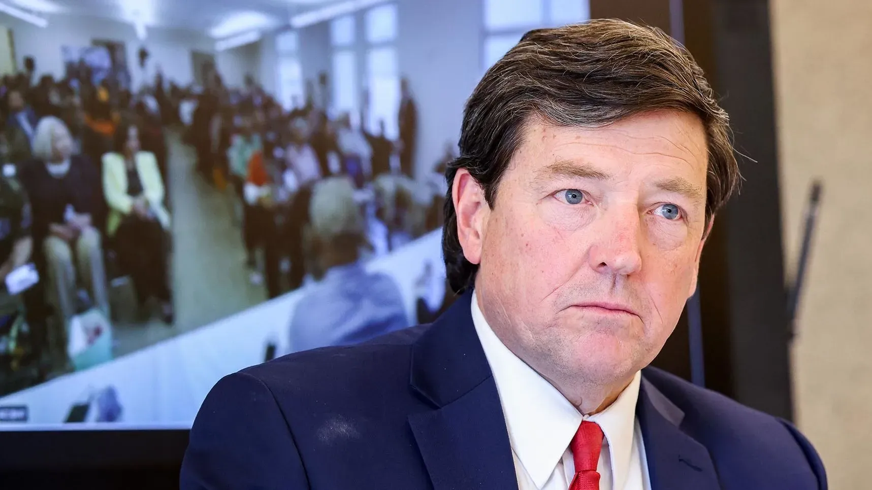 الرجل في الصورة هو إد مارتن، المرشح السابق لمنصب المدعي العام الأمريكي، يجلس أمام حشد كبير خلال مؤتمر صحفي في واشنطن.