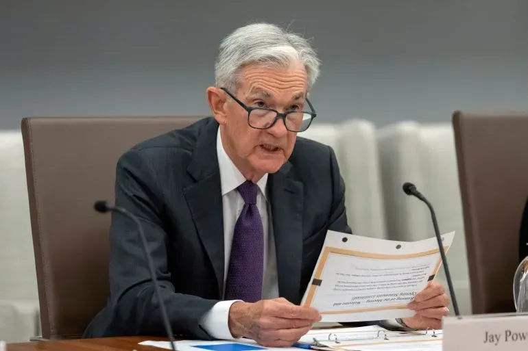 جيروم باول، رئيس مجلس الاحتياطي الفيدرالي، يتحدث خلال اجتماع، مع أوراق في يده، معبرًا عن قلقه بشأن السياسة النقدية.