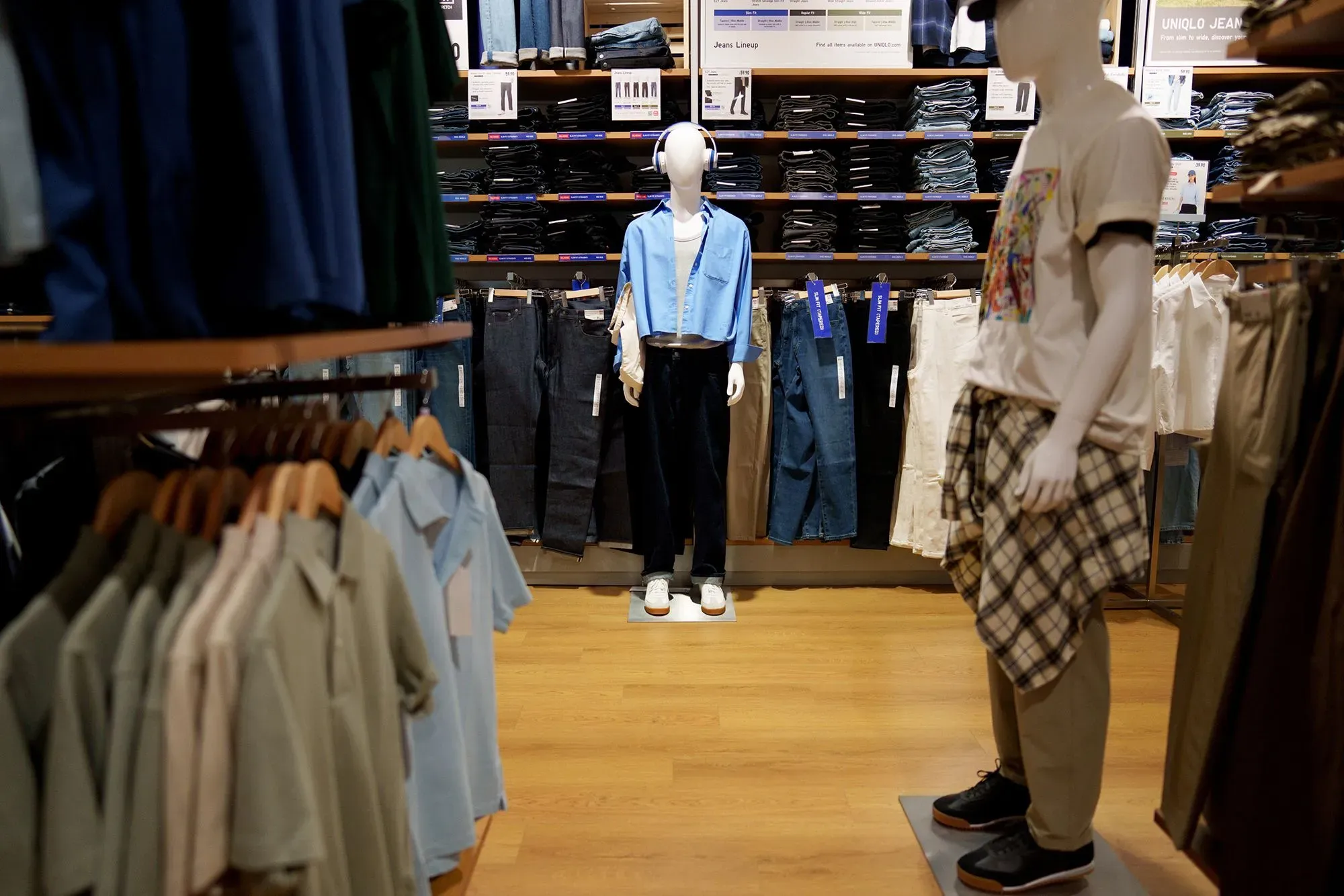 متجر ملابس يعرض مجموعة متنوعة من الأزياء، بما في ذلك قمصان وسراويل، مع دمى عرض ترتدي ملابس جديدة تعكس ارتفاع الأسعار بسبب التعريفات الجمركية.