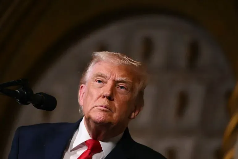 ترامب يتحدث بجدية خلال مؤتمر صحفي، مع التركيز على الضربة الجوية ضد داعش في نيجيريا، في خلفية غامقة.