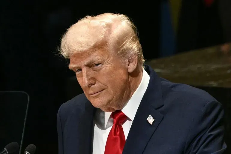 صورة لدونالد ترامب أثناء حديثه، يظهر ببدلة داكنة وقميص أبيض، مع ربطة عنق حمراء، تعكس أجواء التوتر السياسي حول الإغلاق الحكومي.