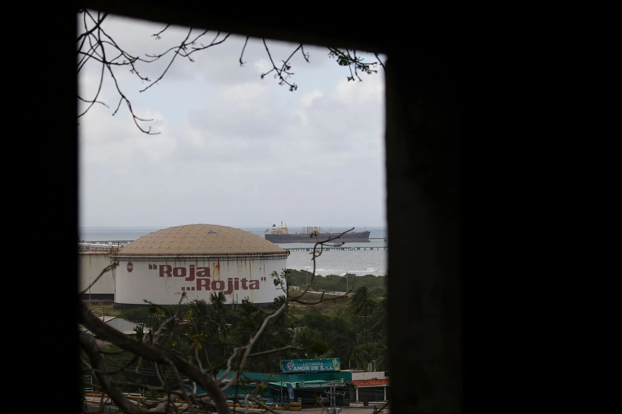 منظر لمستودع نفط يحمل اسم "روخا" في فنزويلا، مع سفينة تجارية ترسو بالقرب من الشاطئ، مما يعكس أهمية النفط في العلاقات الدولية.