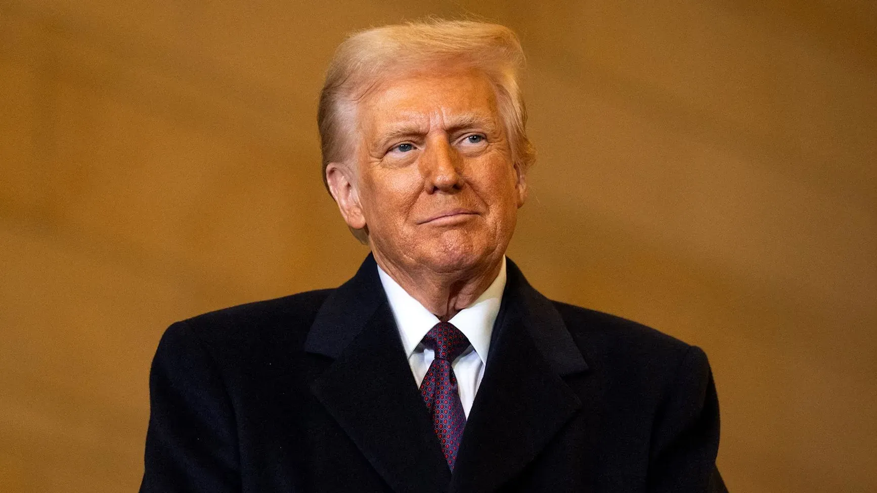 صورة لدونالد ترامب مبتسمًا، يرتدي سترة داكنة وقميص أبيض، خلال مناسبة تتعلق بسياسات الإدارة الفيدرالية.