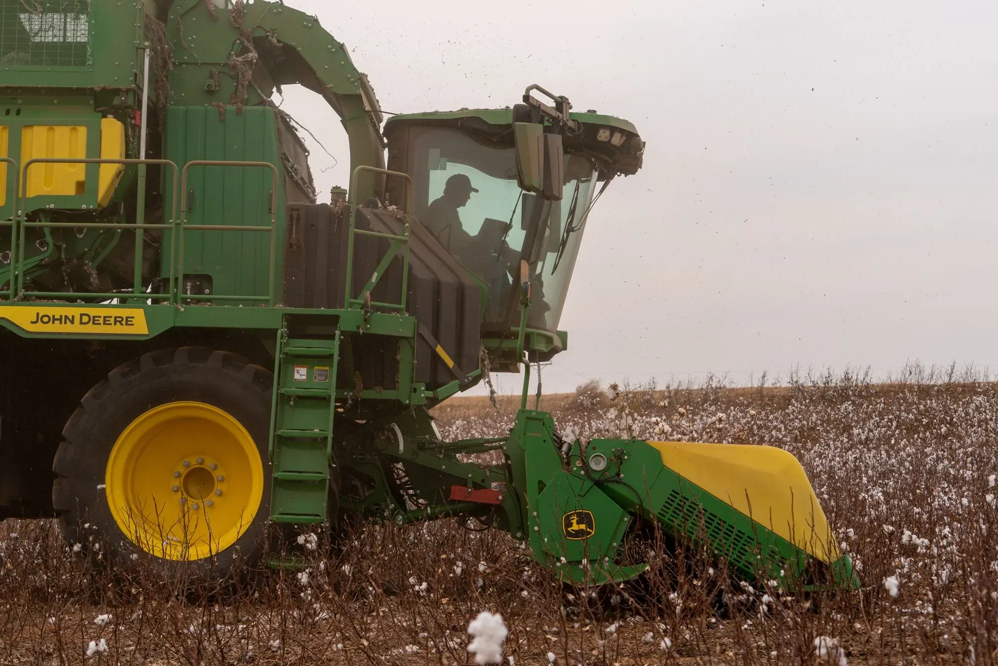 جرار زراعي من نوع "جون دير" يعمل في حقل قطن، مع مزارع داخل المقصورة، في سياق الإعلان عن حزمة مساعدات زراعية بقيمة 12 مليار دولار.