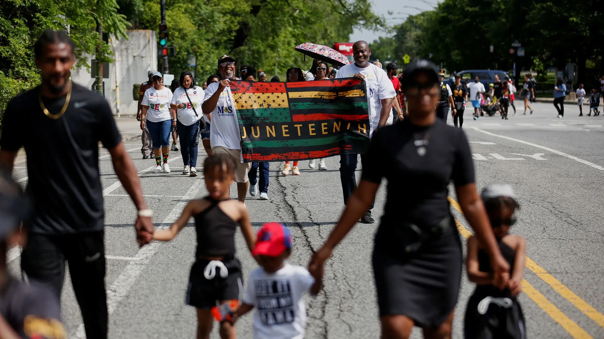 محتفلون يحملون علم يوم جونيتنث خلال مسيرة في الشارع، يعبرون عن الفخر والاحتفال بذكرى تحرير العبيد في الولايات المتحدة.
