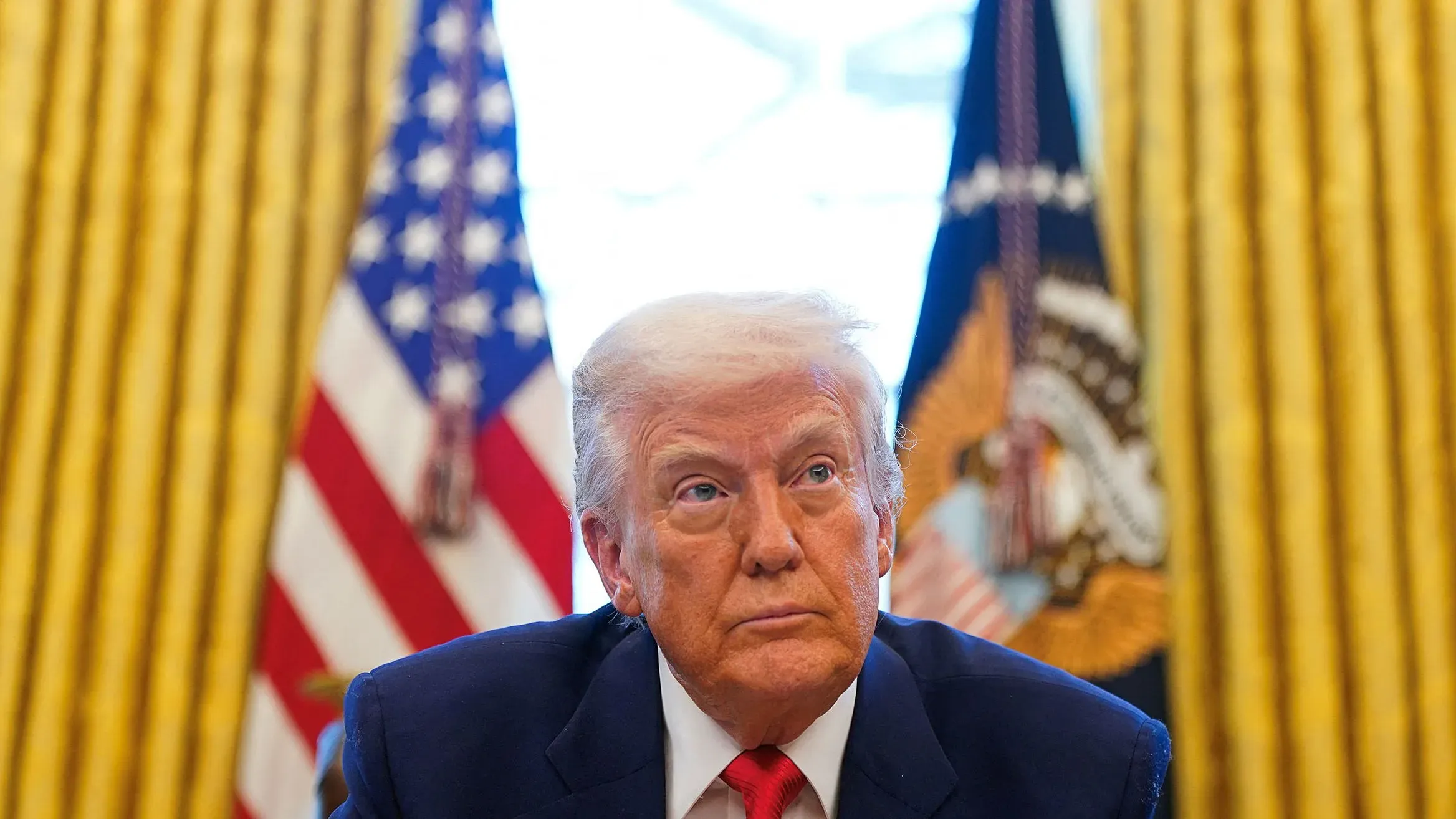 ترامب في المكتب البيضاوي، يعبر عن قلقه بشأن السوق المالية، مع العلميتين الأمريكيتين خلفه، في سياق حديث حول الرسوم الجمركية.