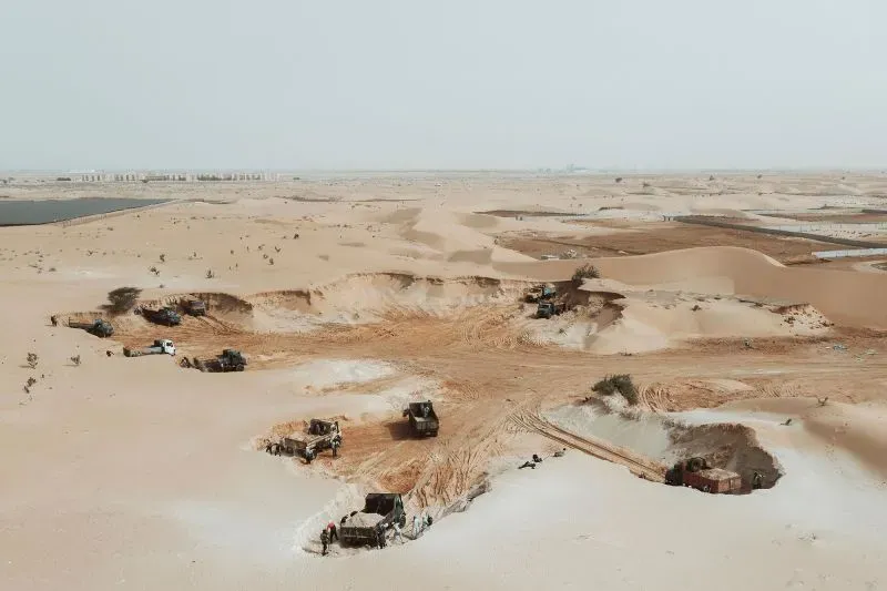 منطقة صحراوية شاسعة تُظهر آلات ثقيلة تعمل في استخراج المعادن، مع وجود حفريات واضحة في الأرض، تعكس الاهتمام الأمريكي بالموارد الطبيعية في أفريقيا.