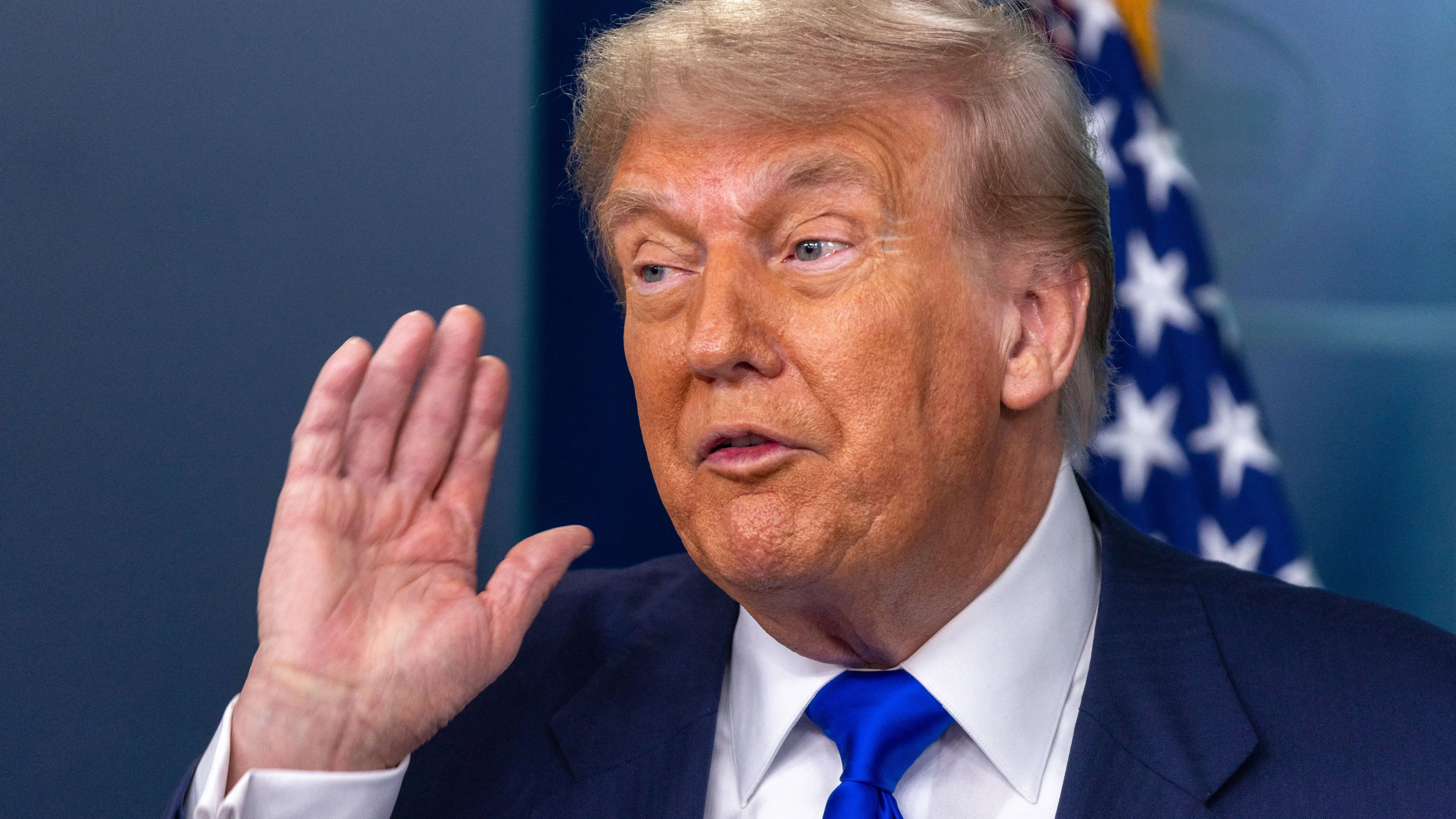 ترامب يتحدث خلال مؤتمر صحفي، مع العلم الأمريكي خلفه، معبرًا عن شكوكه بشأن اتفاق تجاري مع اليابان وتأثير الرسوم الجمركية.