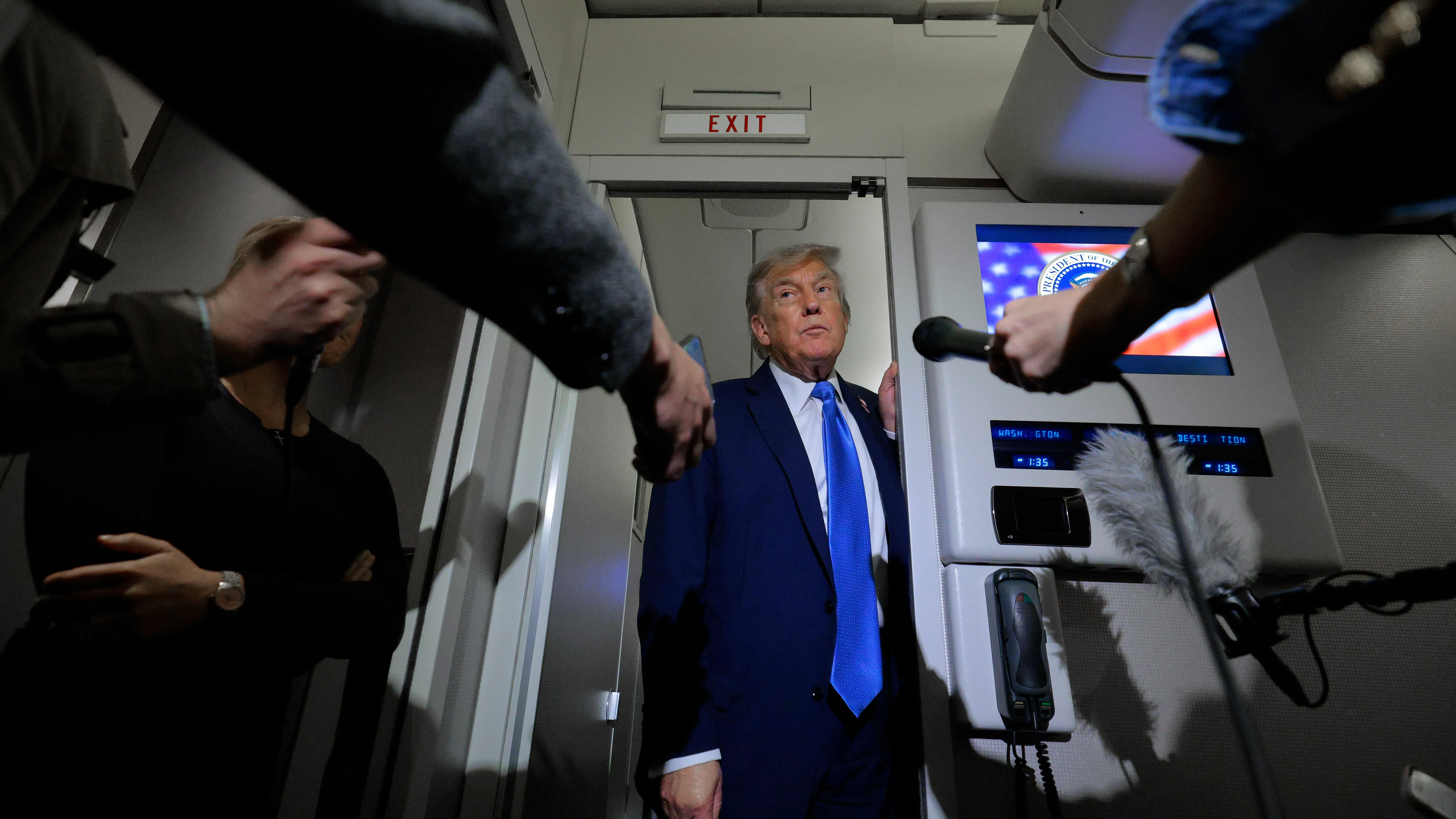 ترامب يقف في ممر الطائرة الرئاسية محاطًا بالصحفيين، بينما يتحدث عن القضايا المثيرة للجدل المتعلقة بتغطية وسائل الإعلام.