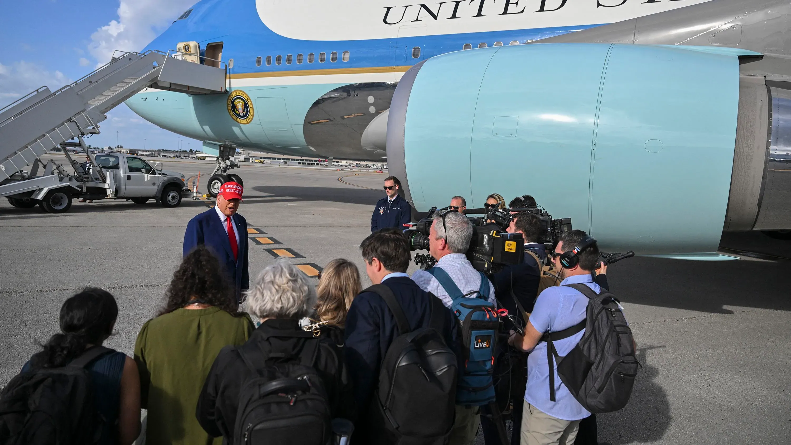 ترامب يتحدث مع الصحفيين أمام طائرة "الولايات المتحدة" أثناء تجمع صحفي، وسط توترات مع وسائل الإعلام التقليدية.