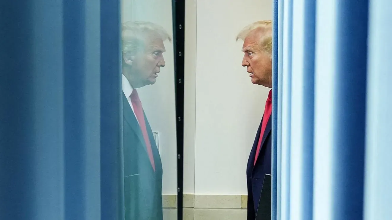 صورة للرئيس دونالد ترامب يراقب نفسه في المرآة وسط أجواء رسمية، تعكس توتر الأوضاع بعد إعلان الرسوم الجمركية الجديدة.